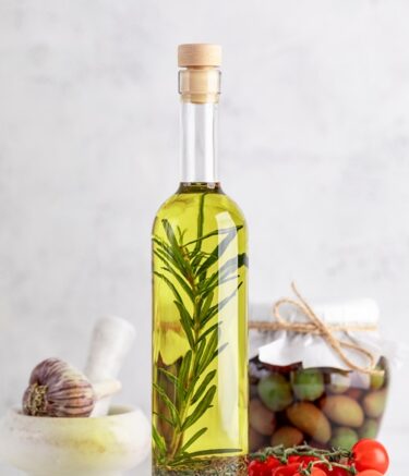 Olive oil with rosemary and garlic on a white background. Vertical